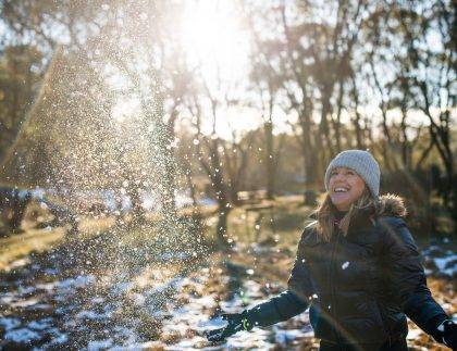 Woman artistically throwing snow in magical lighting in Australian alpine region