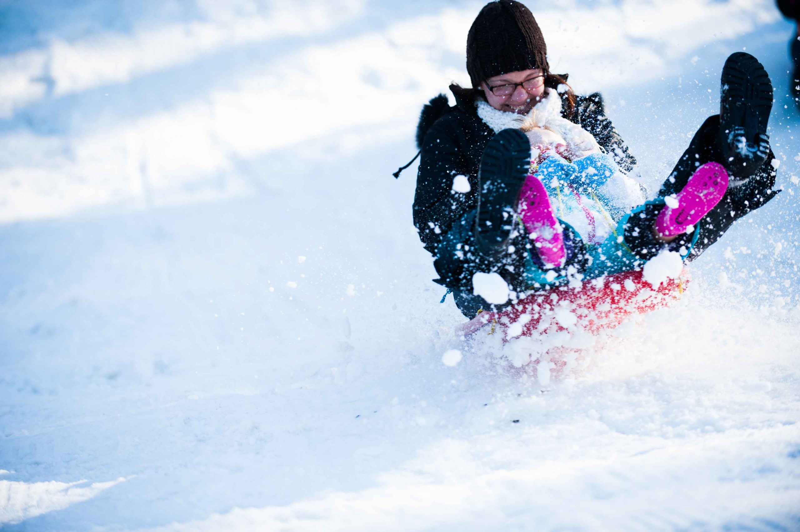 Woman tobogganing fast downhill in snow