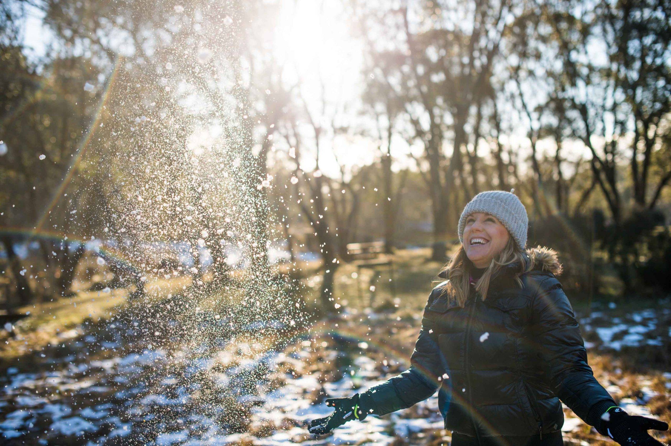 Woman artistically throwing snow in magical lighting in Australian alpine region